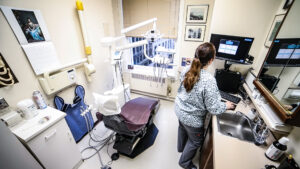 Dental exam room with dental chair and staff member.