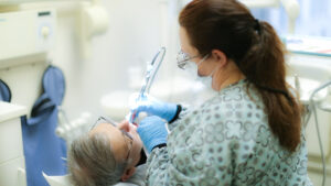 Dental professional working on a patient, using a dental tool.