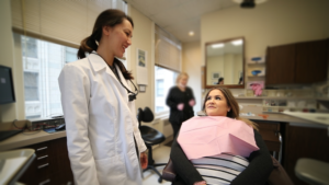 Dentist talking to a patient sitting in a dental chair.