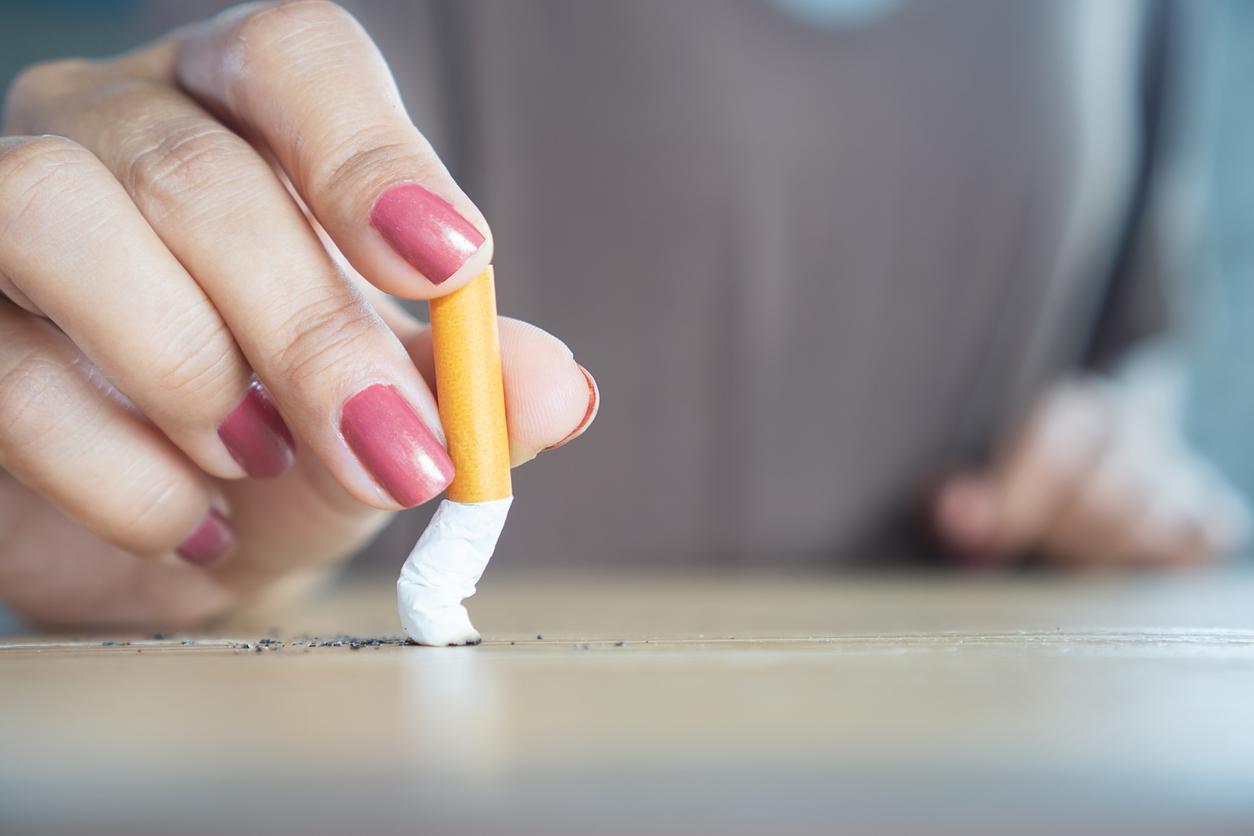 Woman’s hand with pink nails grinding out lit cigarette