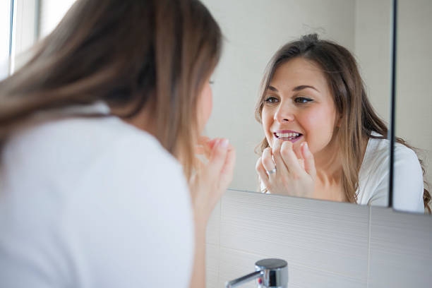 Woman looking at her teeth in the mirror.
