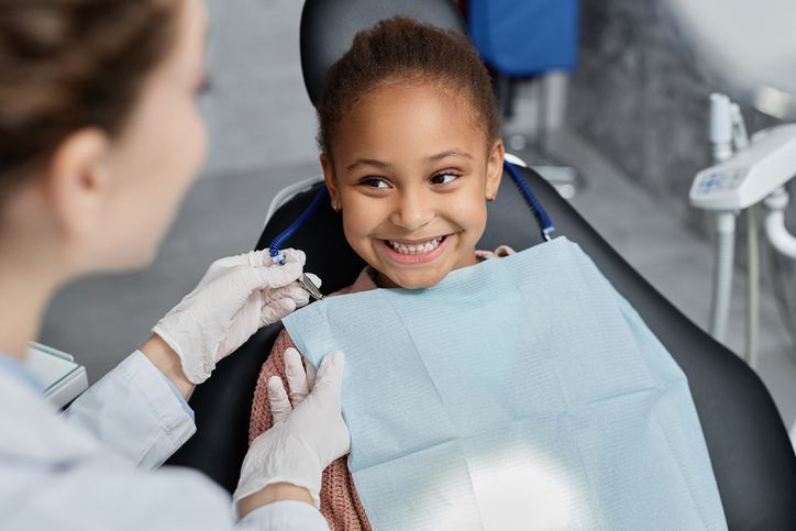 Small girl in dentist chair smiling